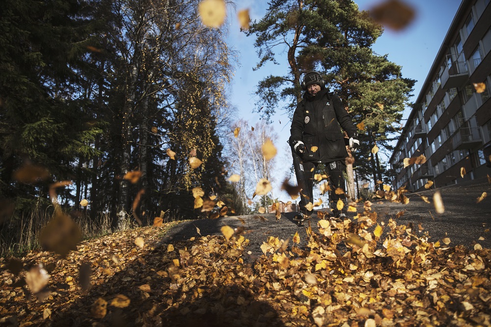 Hekan työntekijä siivoaa pihalta pois puiden pudottamia keltaisia lehtiä.